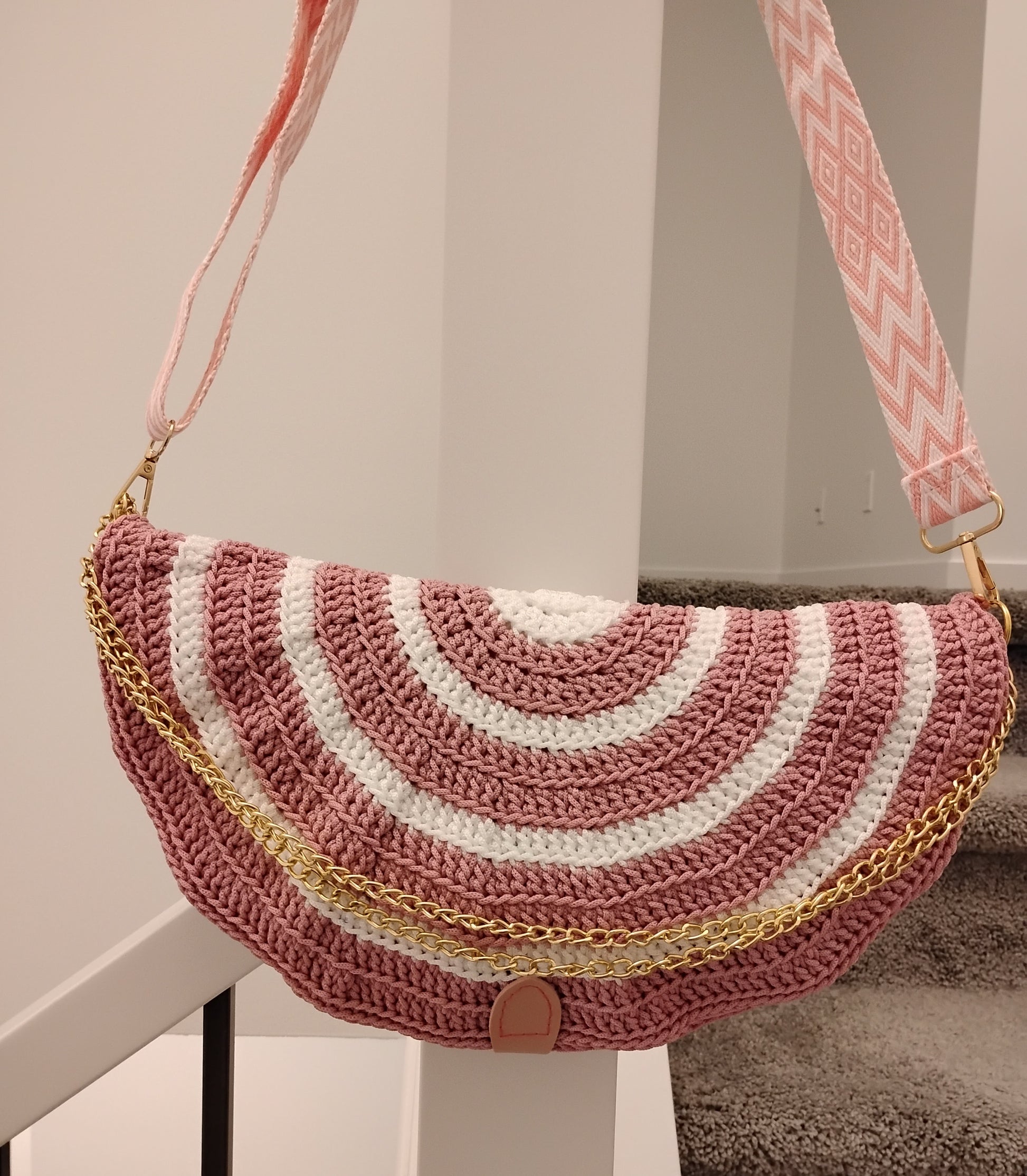 Mid Moon crossbody bag two-tone in crochet design with a pink and white pattern and gold chain detail.